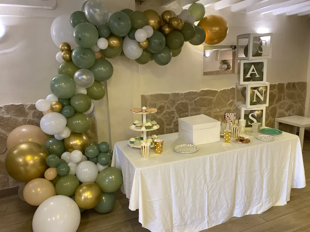 Buffet d'anniversaire enfant avec arche de ballons vert sauge et or