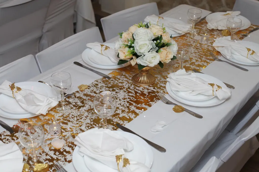 Table de mariage dressée avec chemin de table doré et fleurs blanches