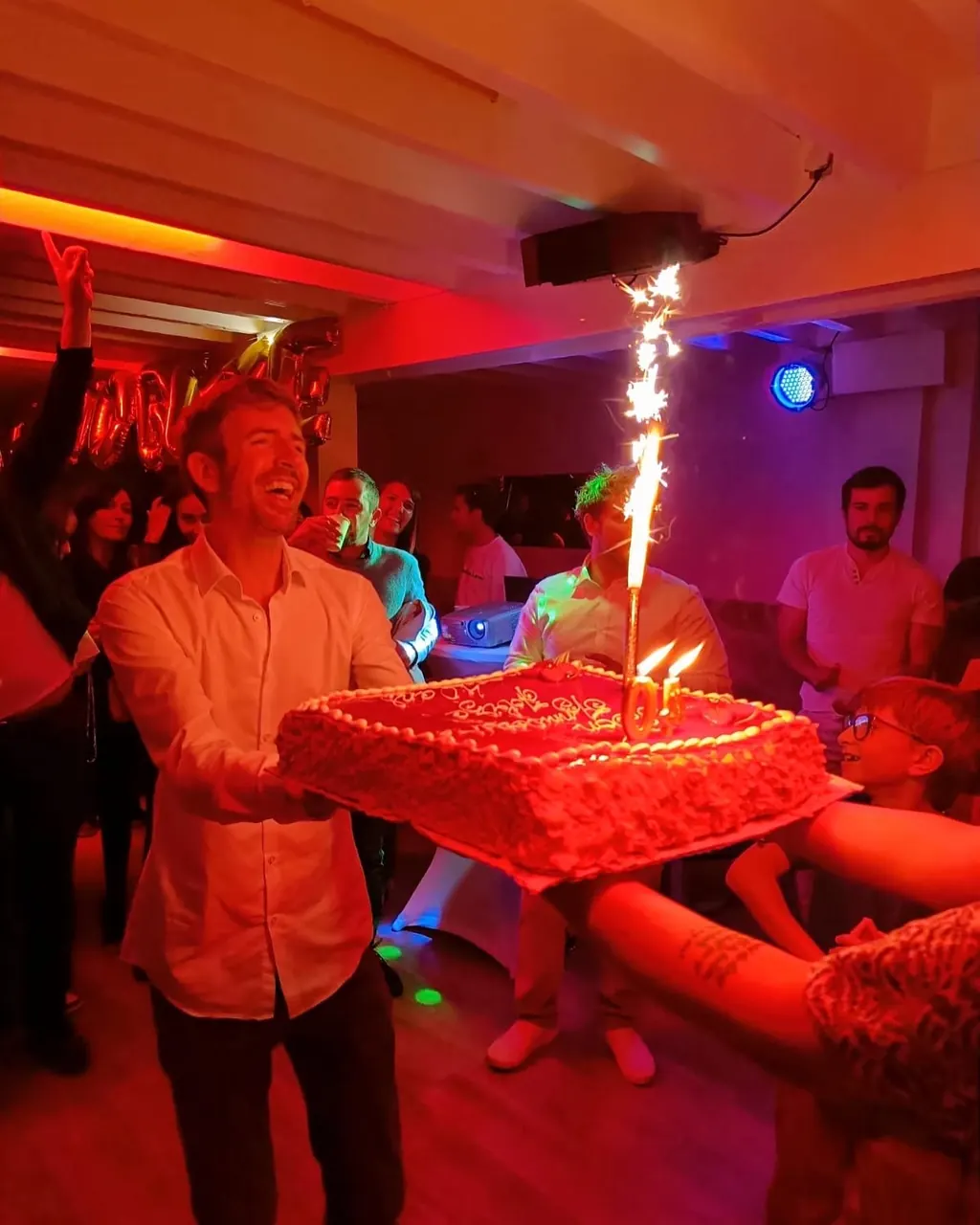 Gâteau avec bougies fontaines au milieu des invités